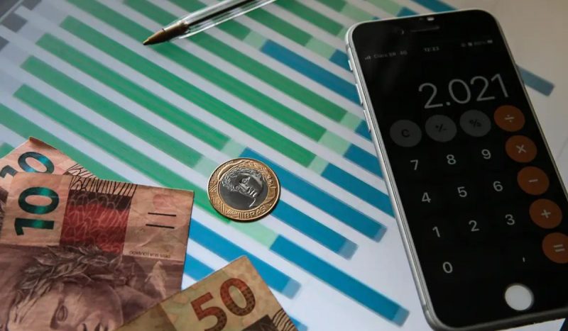 Cédulas de dinheiro e celular com a calculadora aberta