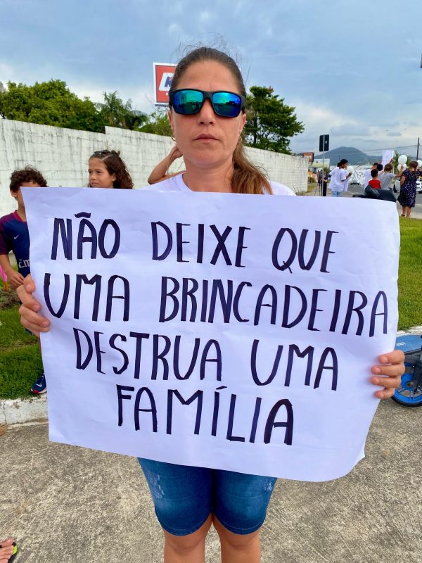 Imagem mostra mulher se manifestando com cartaz contra o uso de cerol em SC