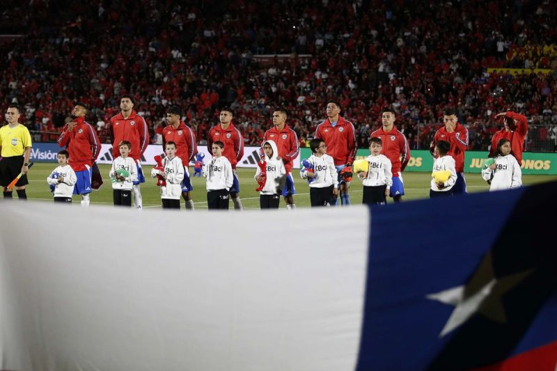 Jogadores da seleção do Chile enfileirados para o hino nacional, com bandeira do Chile em primeiro plano