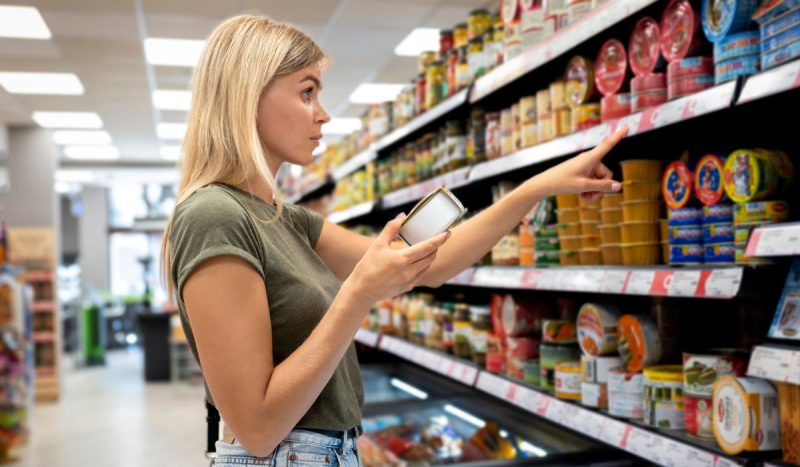 Mulher escolhendo alimentos da cesta básica em supermercado