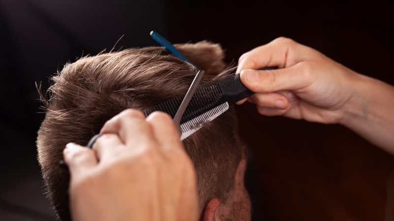 Homem cortando cabelo com pente e tesoura