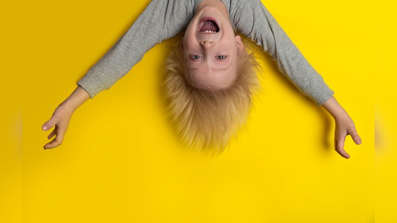 Criança feliz de cabeça para baixo sorrindo