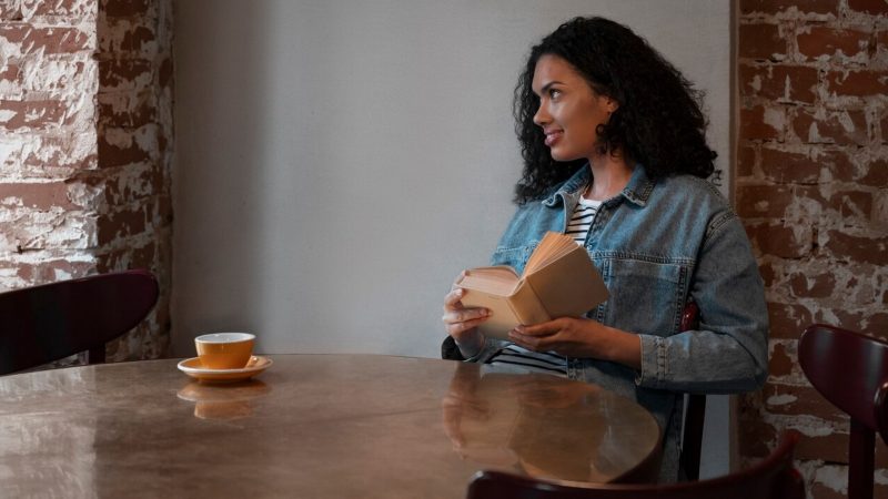 Pessoa com livro na mão e olhando para o lado