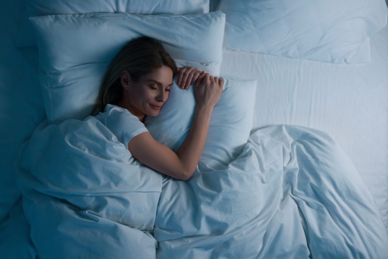 Mulher dormindo na cama à noite, sob efeito do aminoácido glicina