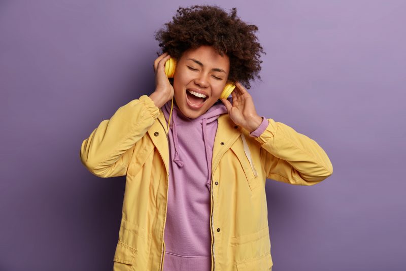 Mulher com fone cantando música que está na sua cabeça