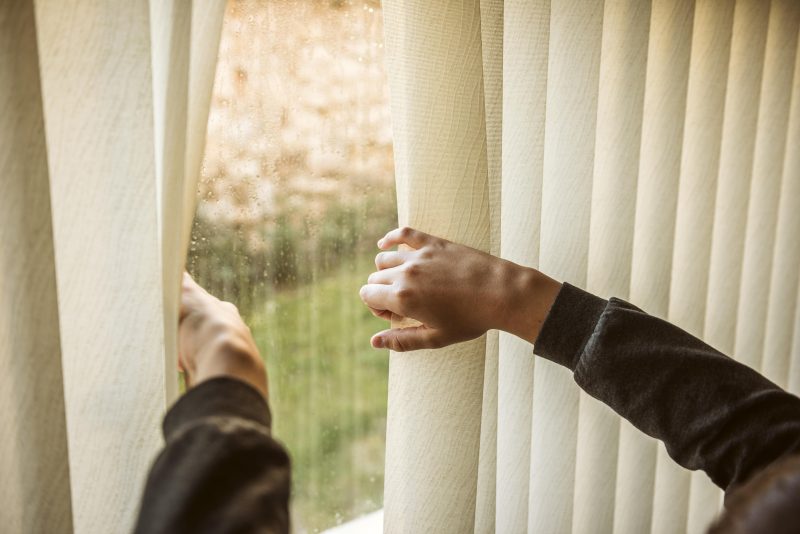 Guia de lavar cortinas Pessoa abrindo a cortina de janela