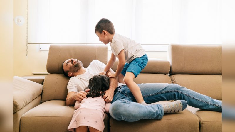 Crianças brincado com homem em cima de sofá