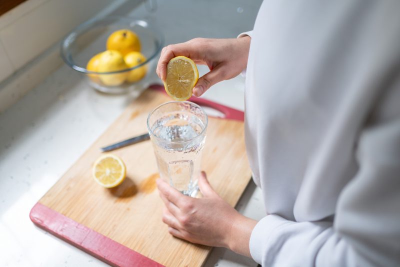 Mulher espremendo suco de limão com água