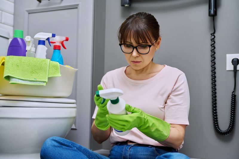 Mulher lendo o rótulo de produtos de limpeza