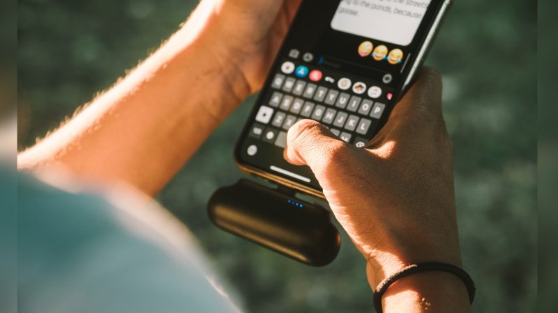 Pessoa segurando na mão um celular mostrando conversas e emojis