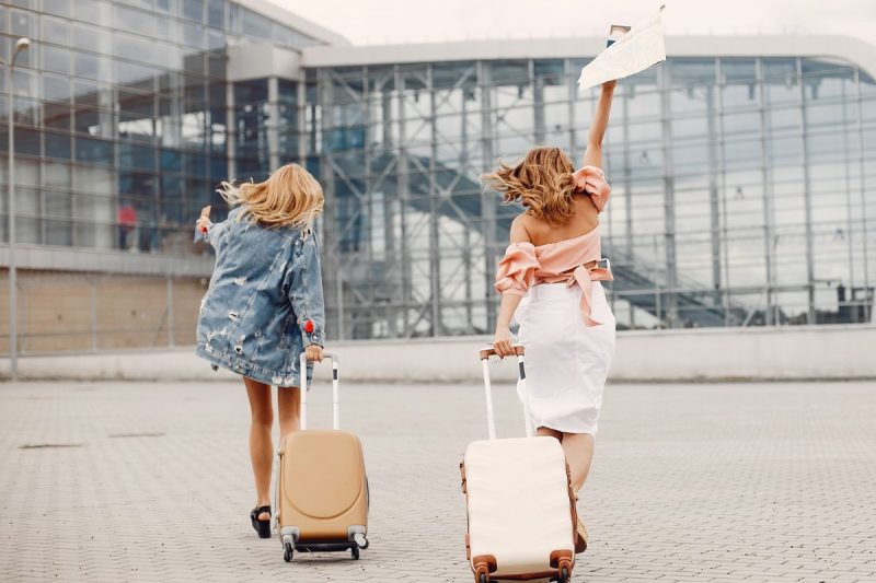 Duas amigas caminhando com malas de viagem para pegar um avião no aeroporto