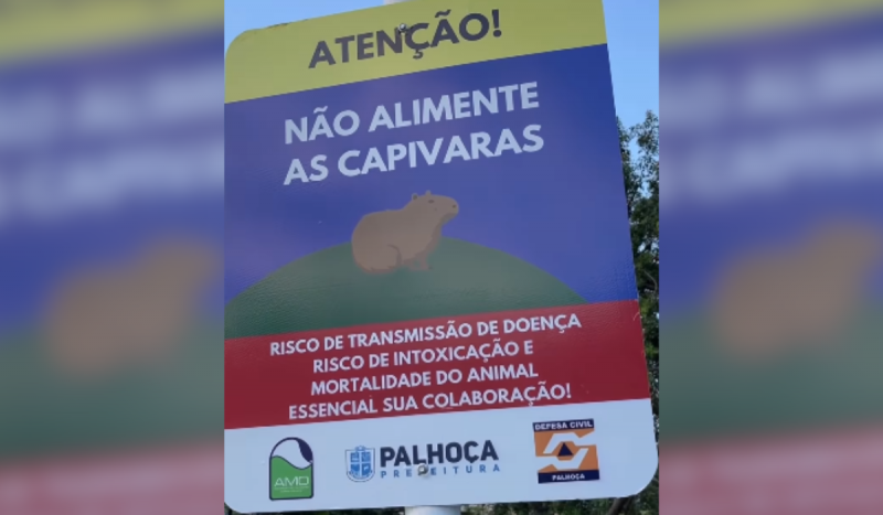 Nova placa escrito "Atenção! / Não alimente as capivaras / Risco de transmissão de doença / risco de intoxicação e mortalidade do animal / essencial sua colaboração"