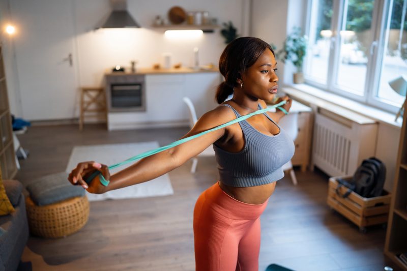 Mulher treinando em casa com elástico