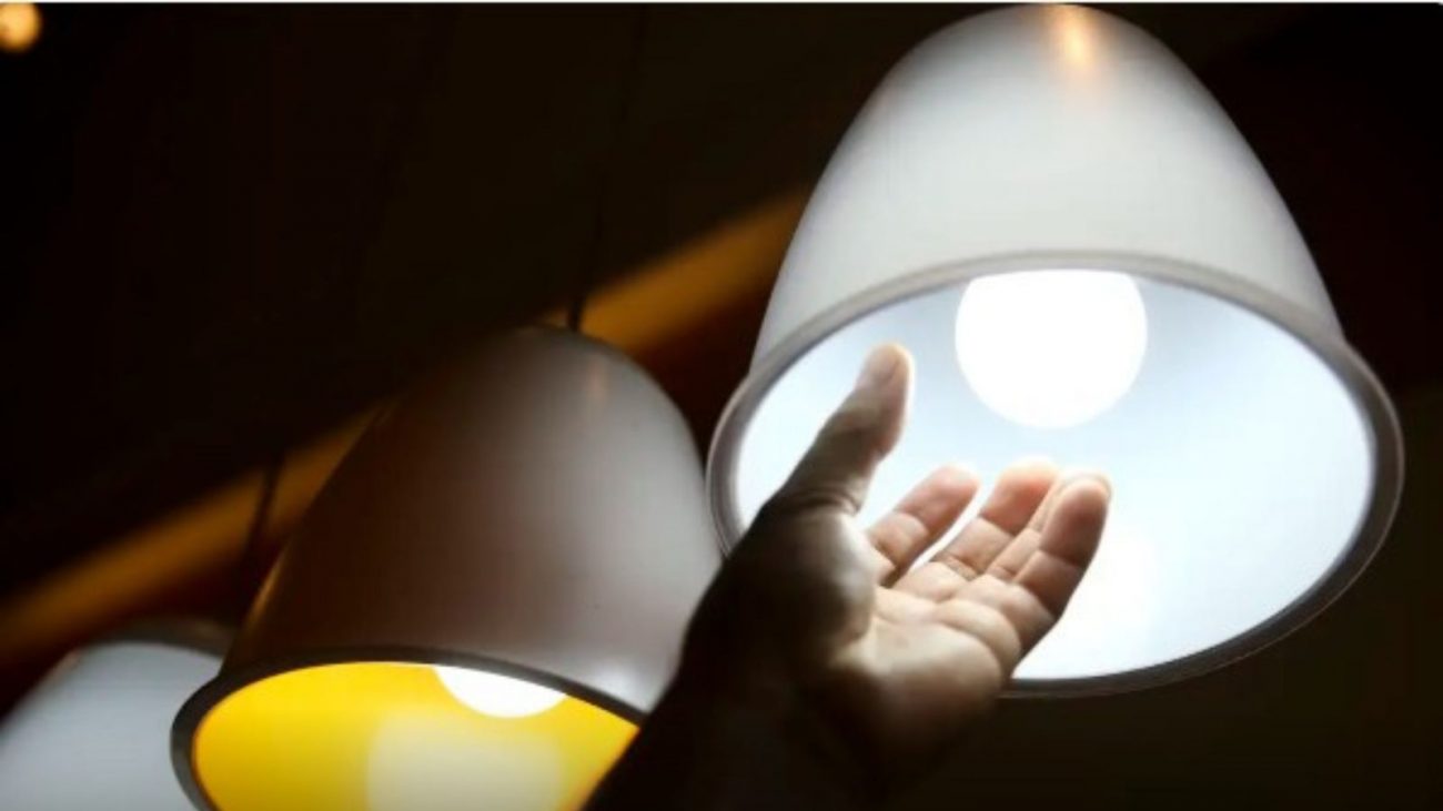 Pessoa mexendo em luminária em matéria sobre conta de luz