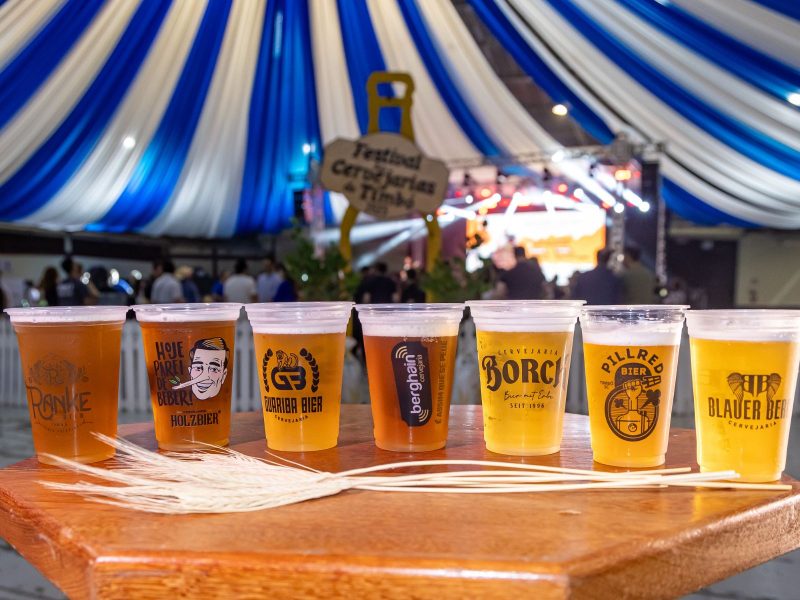 A imagem mostra vários copos de cerveja para ilustrar a matéria do festival gratuito em Timbó. 
