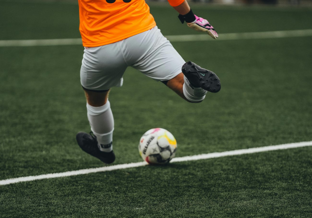 Jogador de futebol em campo chutando a bola. Artigo sobre como apostar em jogo de futebol.