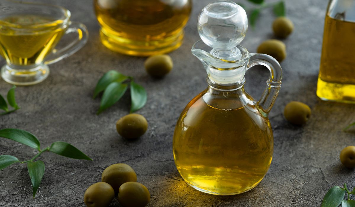 Jarra de vidro com azeite de oliva e azeitonas sobre mesa
