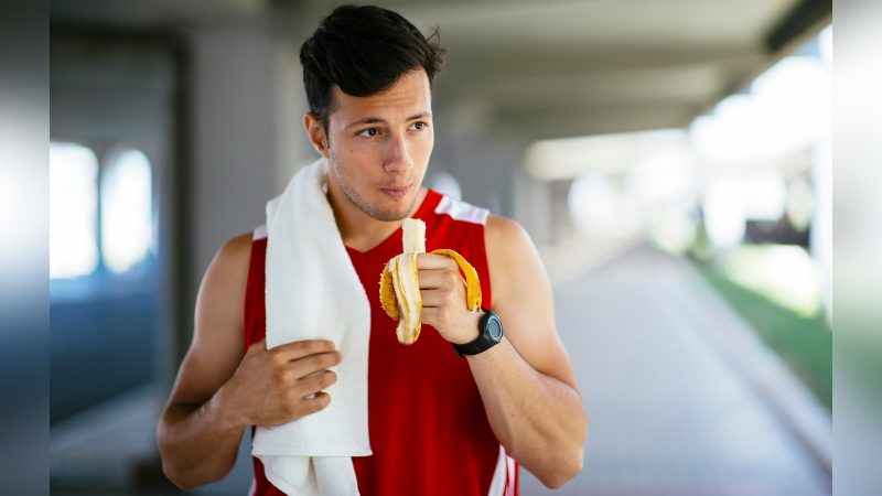 Comer banana Pessoa com roupa de treino comendo banana