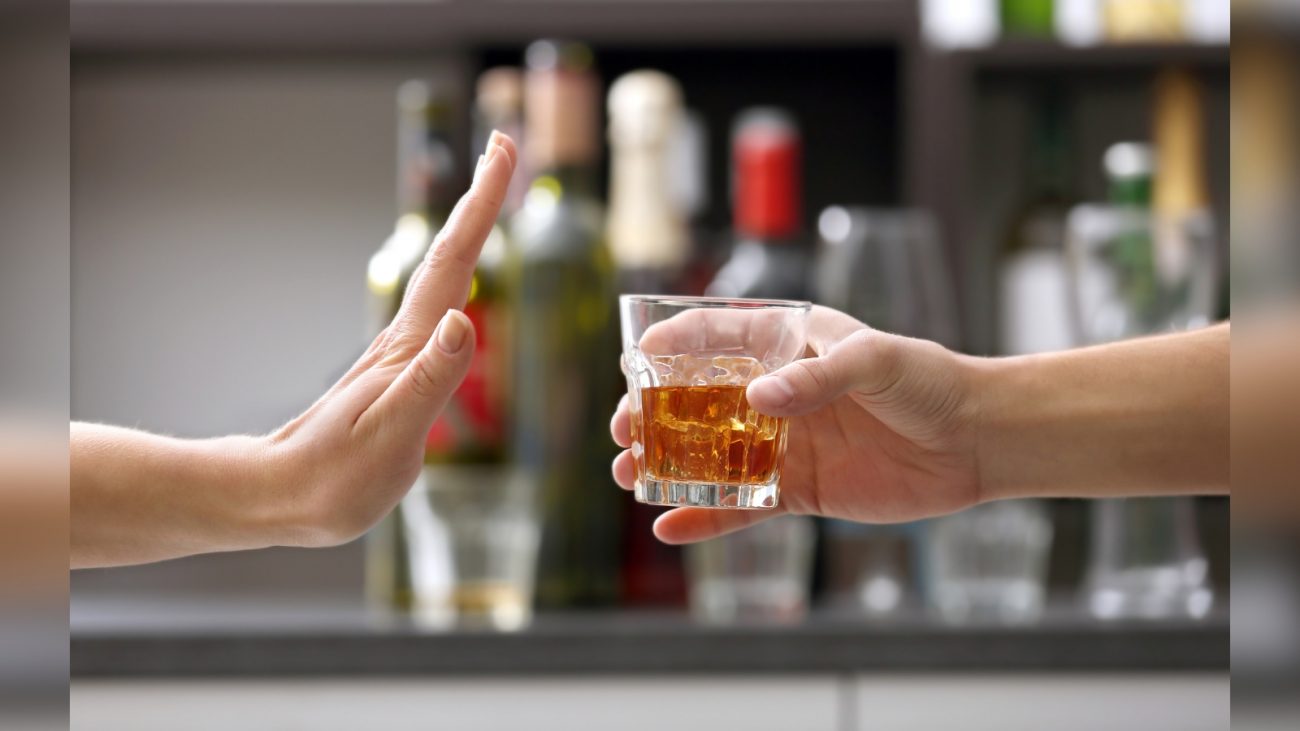 Pessoa recusando copo de bebida alcoólica laranja