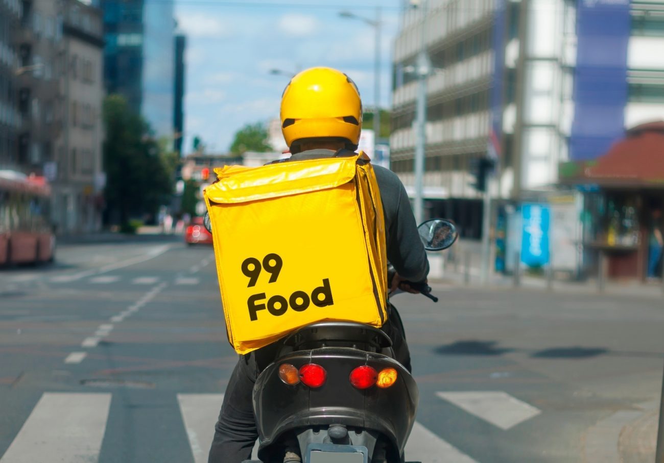 Motociclista com baú adesivado da 99 Food