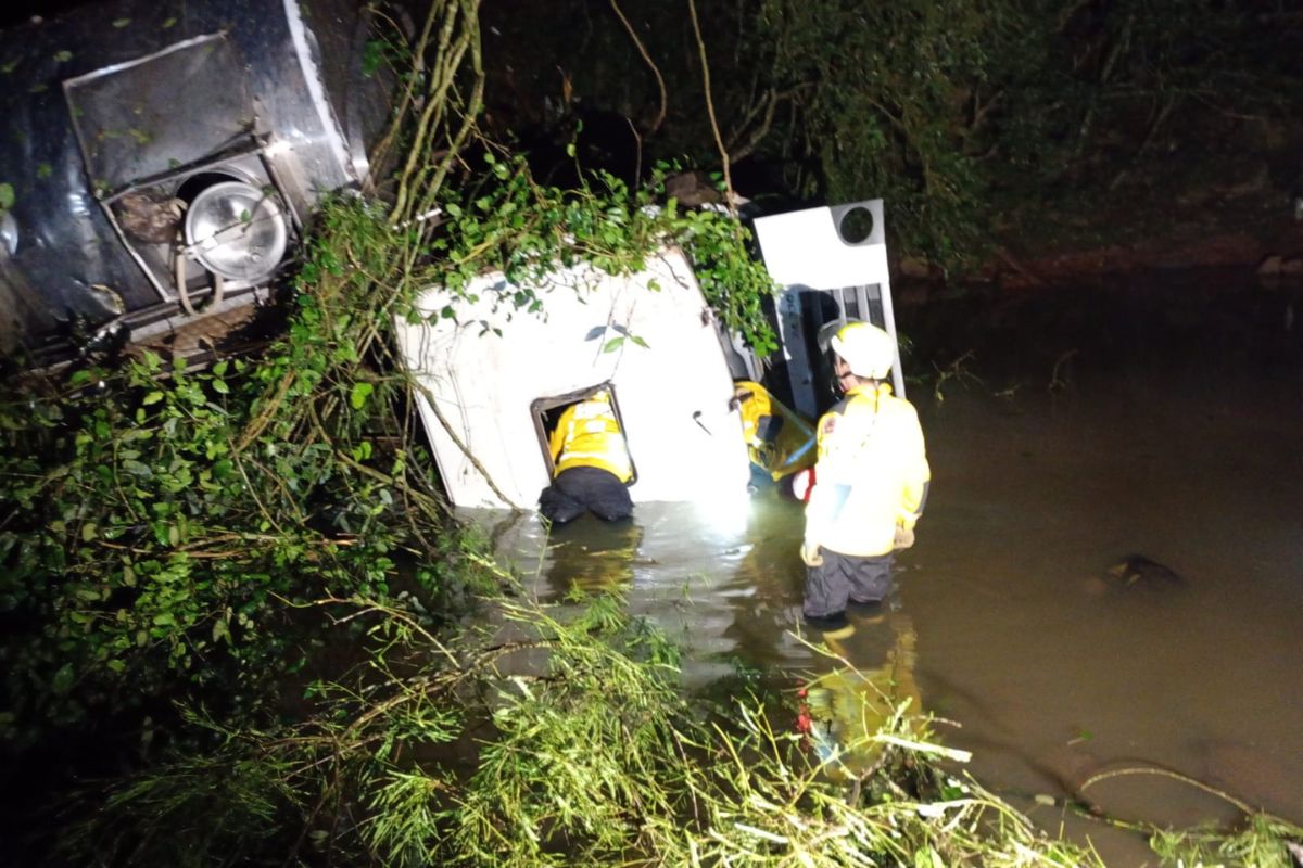 caminhão capotado dentro da água do rio após cair em ribanceira de 35 metros