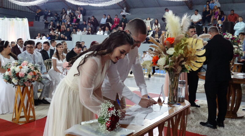 Casamento coletivo Navegantes Noivos assinam documento durante casamento coletivo em Navegantes