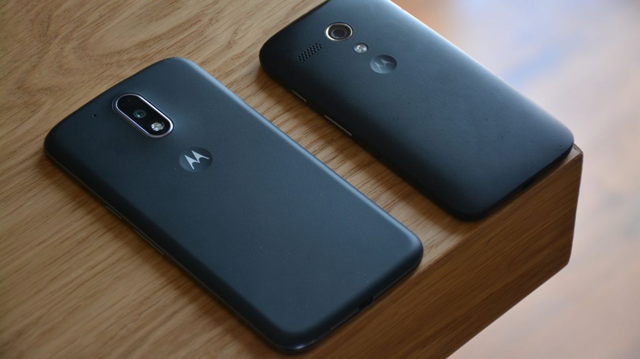 Imagem mostra dois celulares da Motorola virados para baixo em uma mesa de madeira para ilustrar a atualização do Android 16 na marca. 