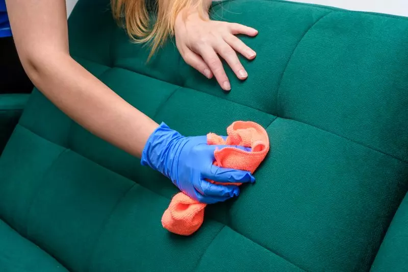 Como posso limpar um sofá de tecido Mulher limpando sofá com pano de flanela para ilustrar como posso limpar um sofá de tecido