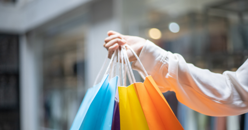 Compras Imagem e uma mulher segurando sacolas de compras coloridas, para fazer referência ao sábado especial do comércio em Criciúma