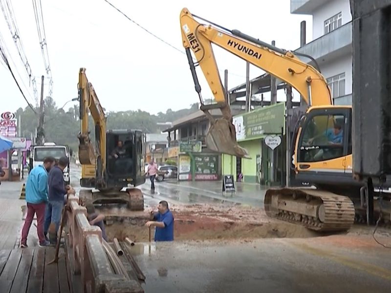 cratera em ponte em Brusque Imagem mostra uma cratera gigante aberta em rua Botuverá de Brusque, no Vale do Itajaí. Na foto é possível ver duas máquinas trabalhando na via, além de três homens acompanhando o serviço