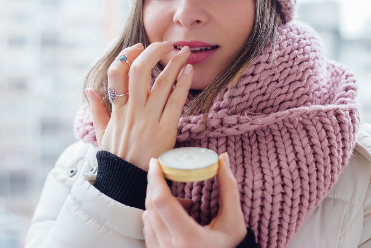 Cuidados com lábio inverno Mulher usando protetor labial para representar cuidados com lábio e skincare no inverno