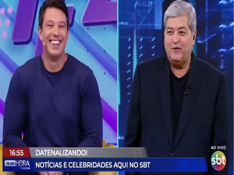 Imagem mostra dois homem conversando e sorrindo. Um veste uma camisa azul escura e outro veste um paletó todo na cor preta, Um deles tem cabelo escuro e outro já é grisalha. Eles são dois apresentadores da emissora SBT e há rumores de que Datena está de saída do SBT 