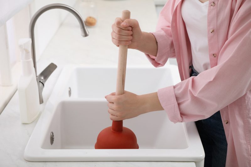 Desentupir pias Mulher tentando desentupir pias