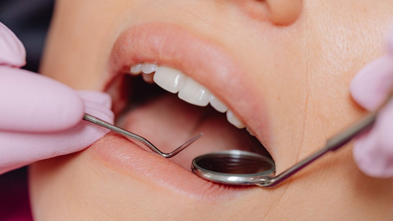 Dentista mexendo na boca de uma paciente mulher