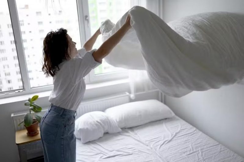 Roupa de cama Mulher estendendo edredom na cama