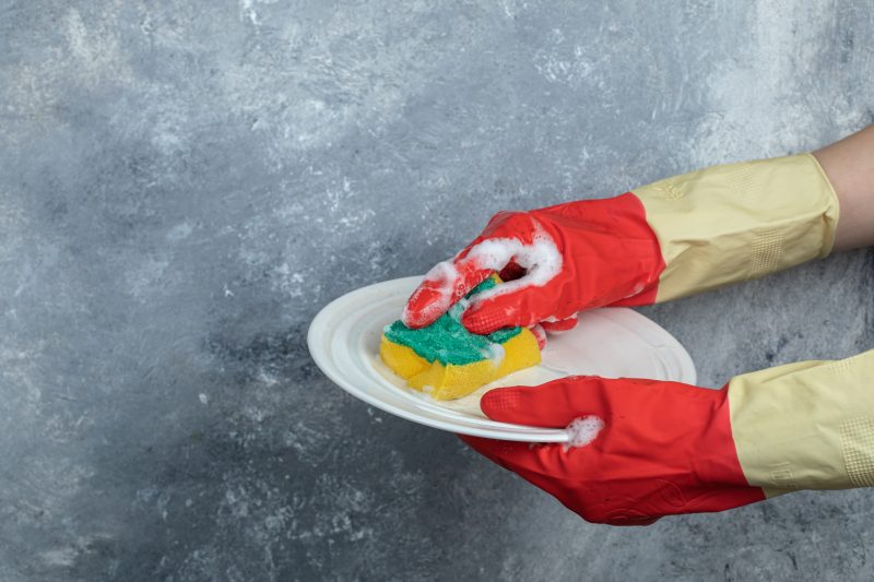 Pessoa esfregando um prato Pessoa esfregando um prato com uma esponja e espuma de detergente