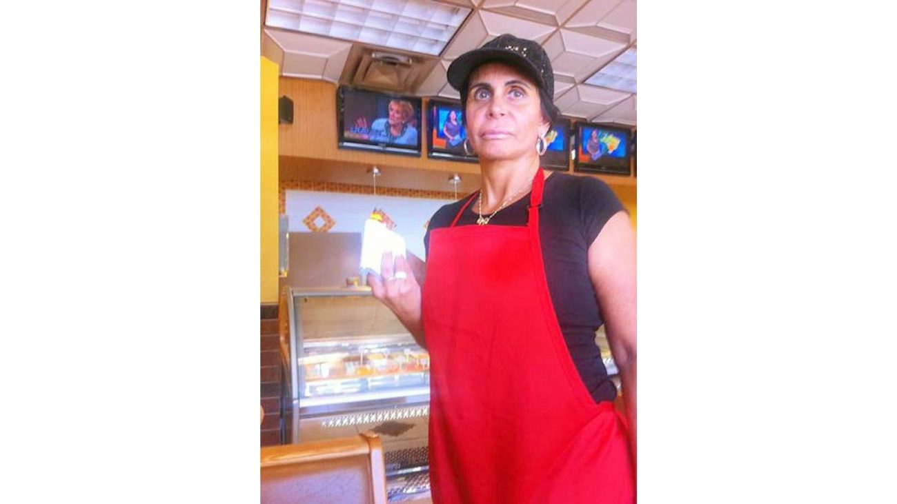 Gretchen Imagem mostra a cantora Gretchen com uma roupa preta, um avental vermelho em uma lanchonete ou restaurante para ilustrar porque a Gretchen não pode entrar nos Estados Unidos atualmente.