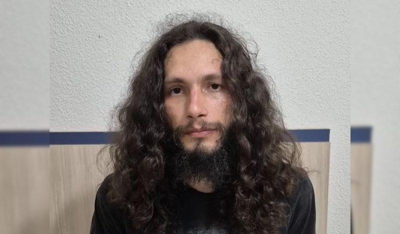 Professor de canto que oferecia "chá de sêmen" já foi processado por outros crimes sexuais Professor de canto que oferecia "chá de sêmen" já foi processado por outros crimes sexuais. Na imagem, ele aparece centralizado, com expressão séria. Homem branco, de cabelos cacheados castanhos longos, com barba cavanhaque longa.