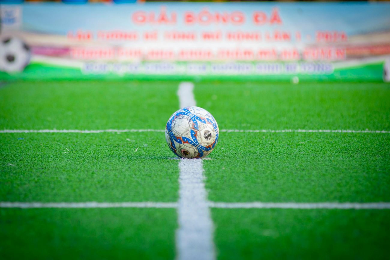 Campo de futebol com a bola no meio de campa representando o handicap asiático em apostas.