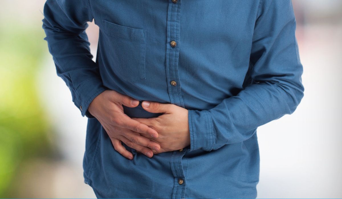 Pessoa com as mãos sobre o lado direito do abdomen