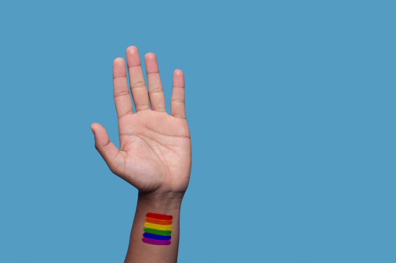 Mão levantada com pintura da bandeira LGBT Foto de mão levantada com a pintura da bandeira LGBT ilustra matéria sobre homem condenado por homofobia em Balneário Camboriú