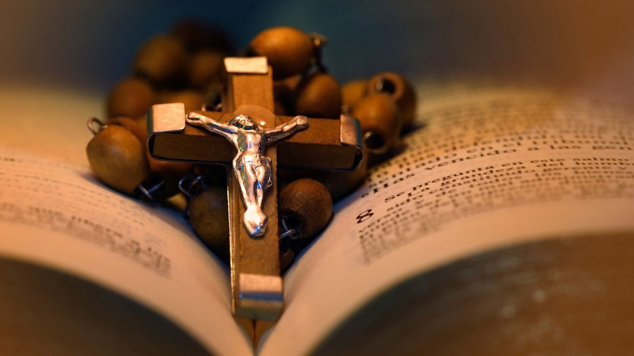 Bíblia Imagem mostra uma bíblia com um terço preto em cima para simbolizar o santo do dia.