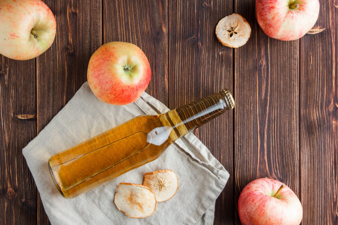 Vinagre de maçã Vinagre de maçã sobre uma mesa de madeira ao lado das furtas
