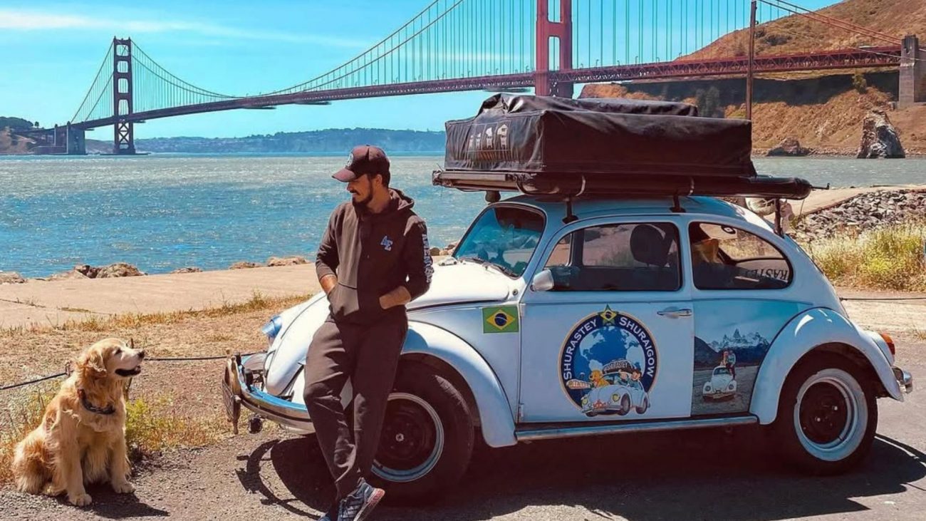 Jesse e Shurastey Foto mostra Jesse e Shurastey ao lado de fusca durante viagem nos EUA