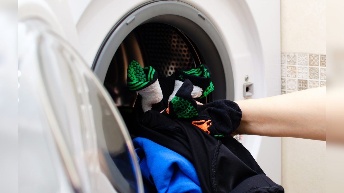 Lavar roupas esportivas Imagem de pessoa colocando roupas esportivas dentro de máquina de lavar