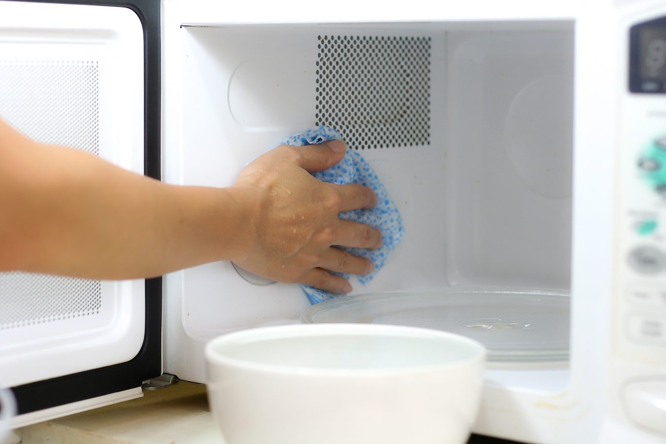 Limpando o micro-ondas Pessoa limpando o micro-ondas