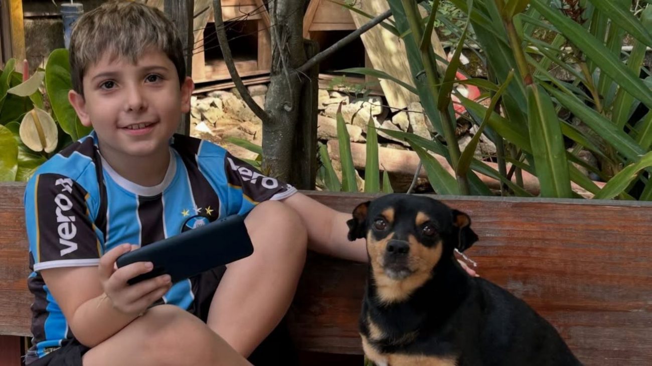 Imagem de Vitor, menino de 9 anos que sofreu AVC, ao lado de um cachorro