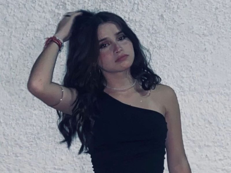Acidente com scooter Imagem mostra uma adolescente menina, com vestido preto, cabelos escuros solto, fazendo pose para foto. Ela usa no pulso várias pulseiras e segura o cabelo com uma das mãos. A jovem morreu em acidente com scooter, em Brusque, no Vale do Itajaí