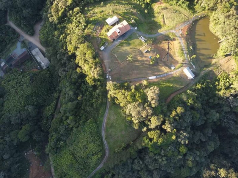 Cabana de Pedra Imagem mostra uma propriedade vista de cima. É possível ver muitas árvores e montanhas verdes. Também é possível enxergar caminhos, ruas de barro de cima, além de algumas construições