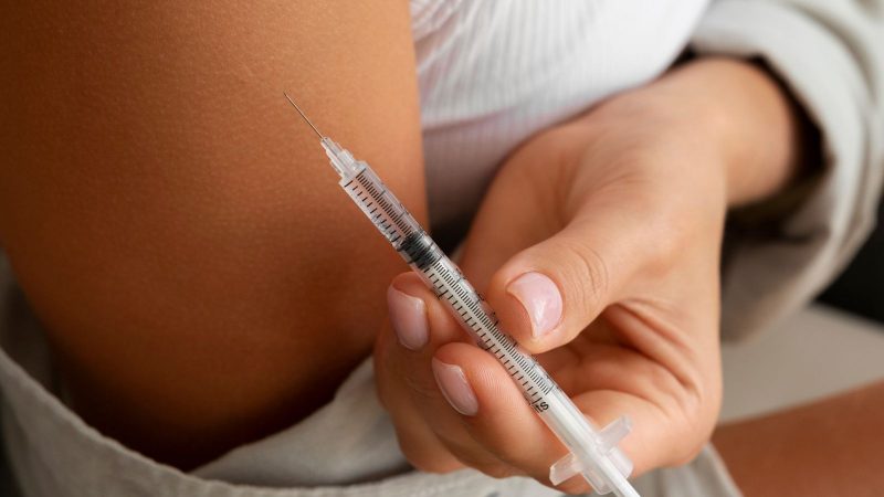 Mulher aplicando uma injeção de testosterona no braço